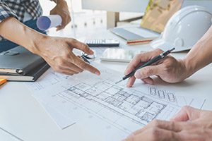 engineer Hand Drawing Plan On Blue Print with architect equipment discussing the floor plans over blueprint architectural plans at table in a modern office